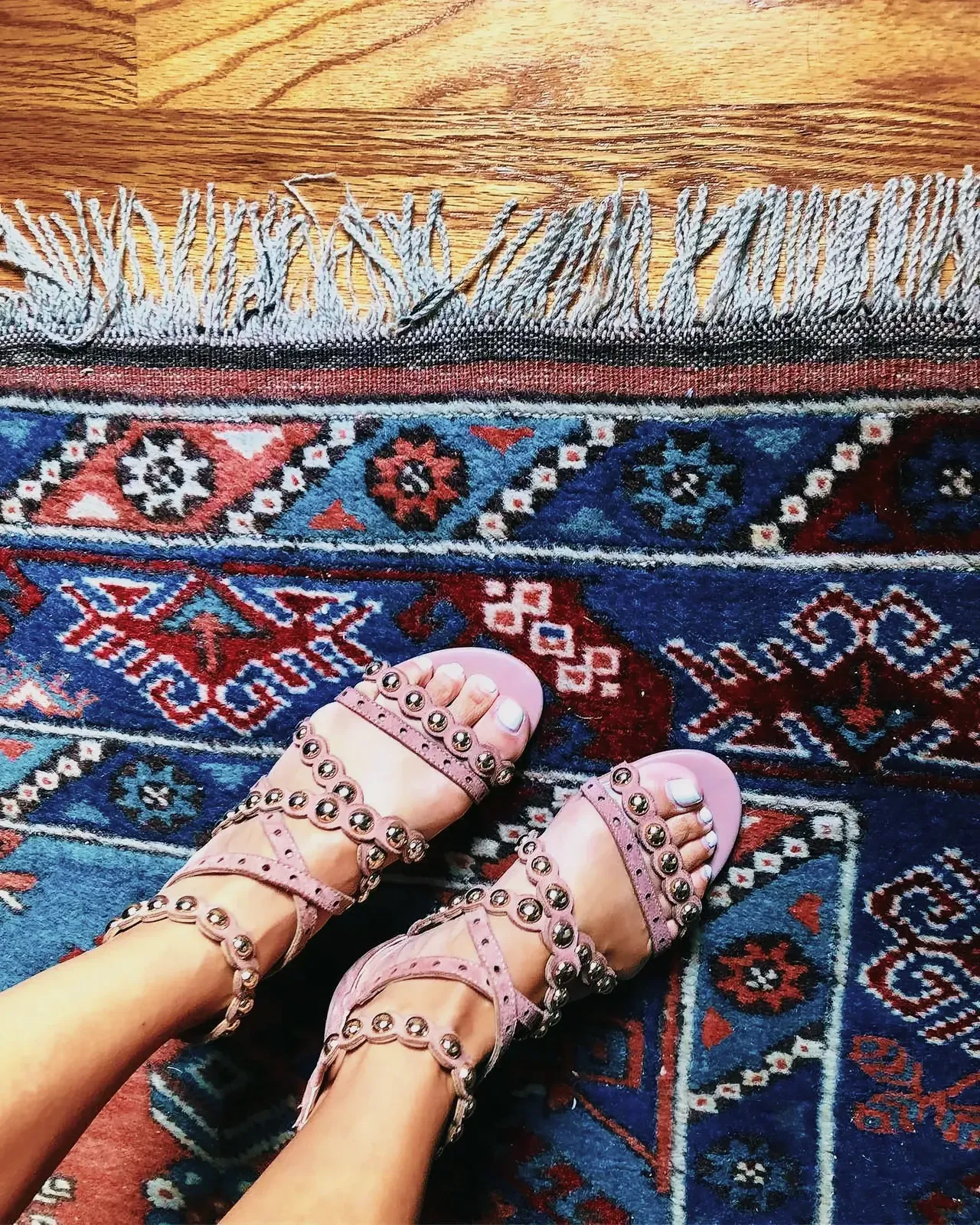 Close-up view of Sam Edelman leather sandals on an artful rug with a fringe.