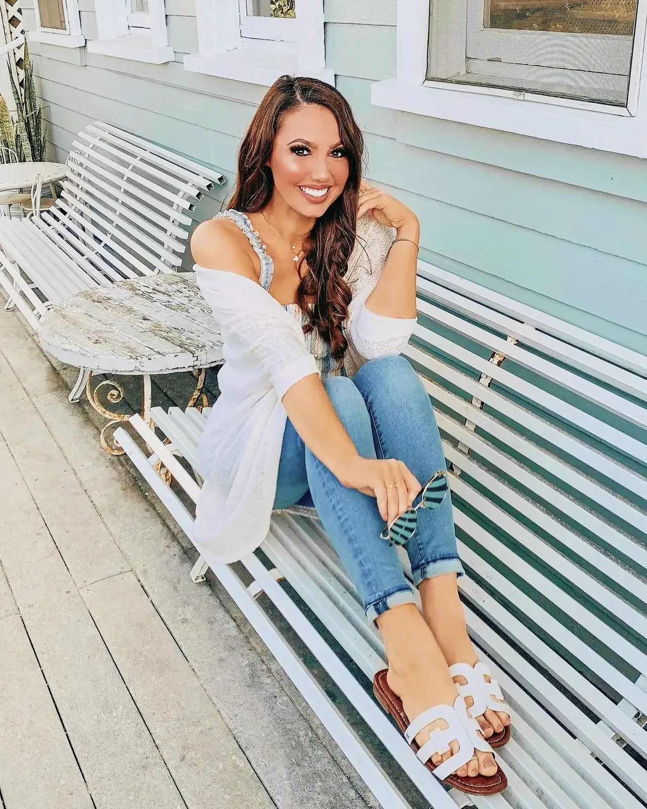 Woman sitting on a wooden bench wearing stylish Sam Edelman leather sandals.
