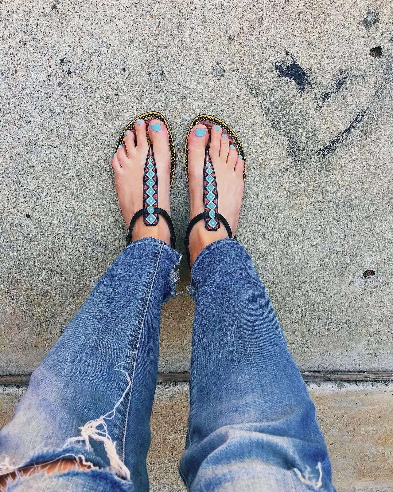 Stylish and affordable Sam Edelman Leather Sandals with tribal pattern, painted toenails, and rolled-up denim jeans.