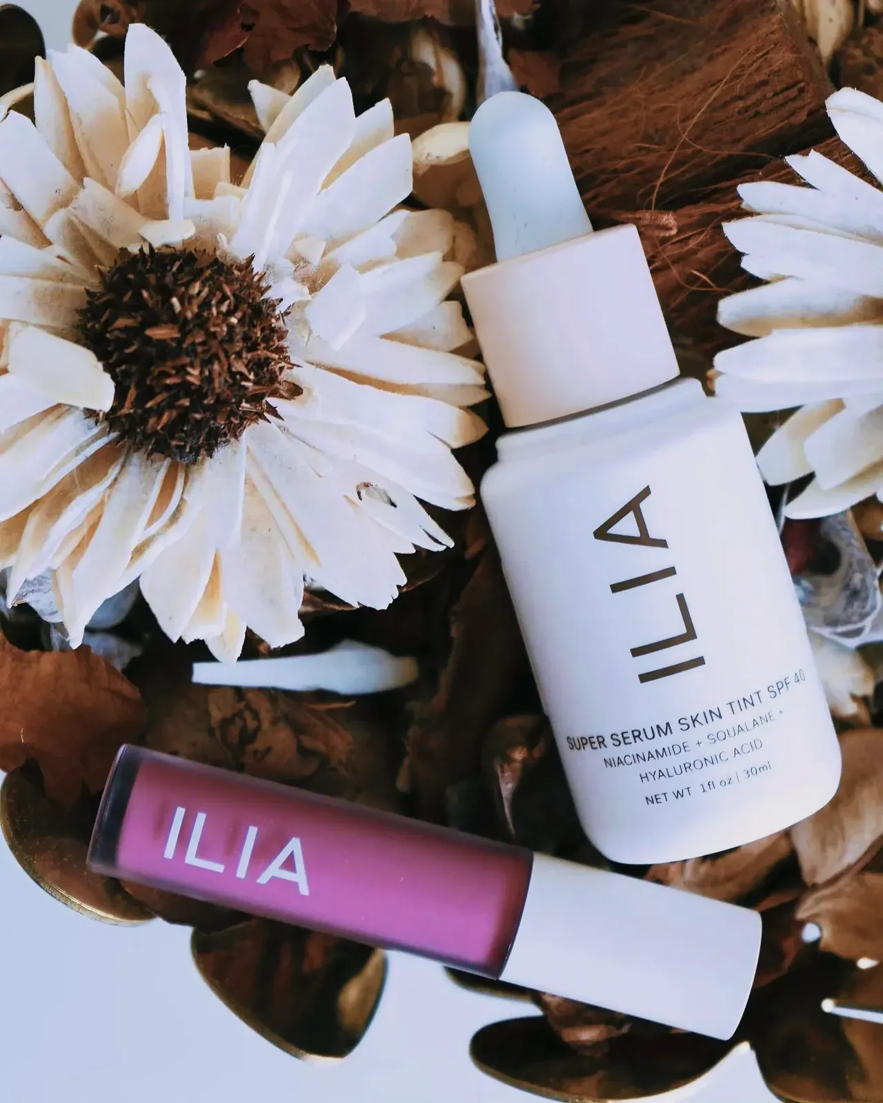 ILIA Super Serum Skin Tint SPF 40 bottle surrounded by sunflowers