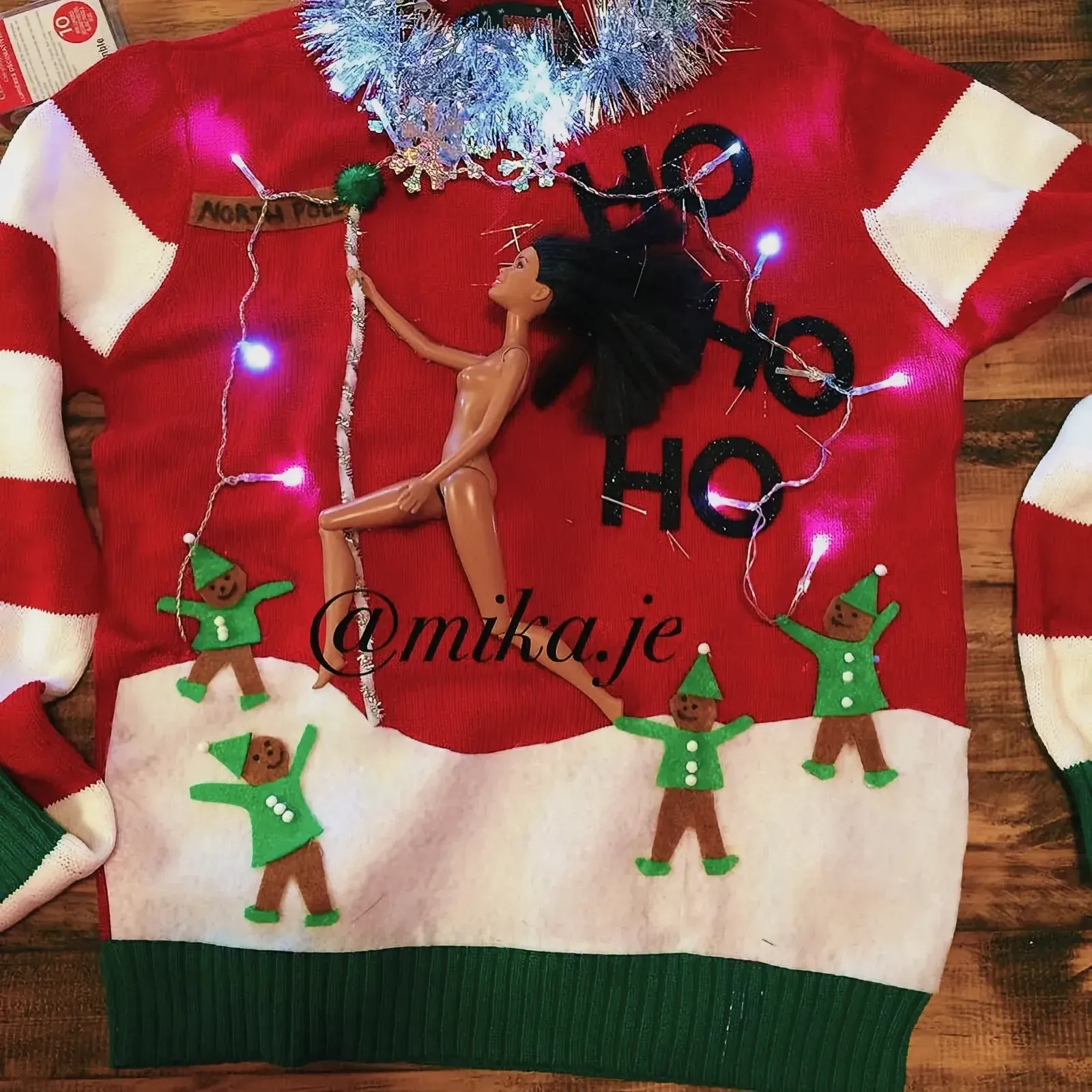 Charming DIY Christmas sweater adorned with a doll figure, a garland, and festive decorations.