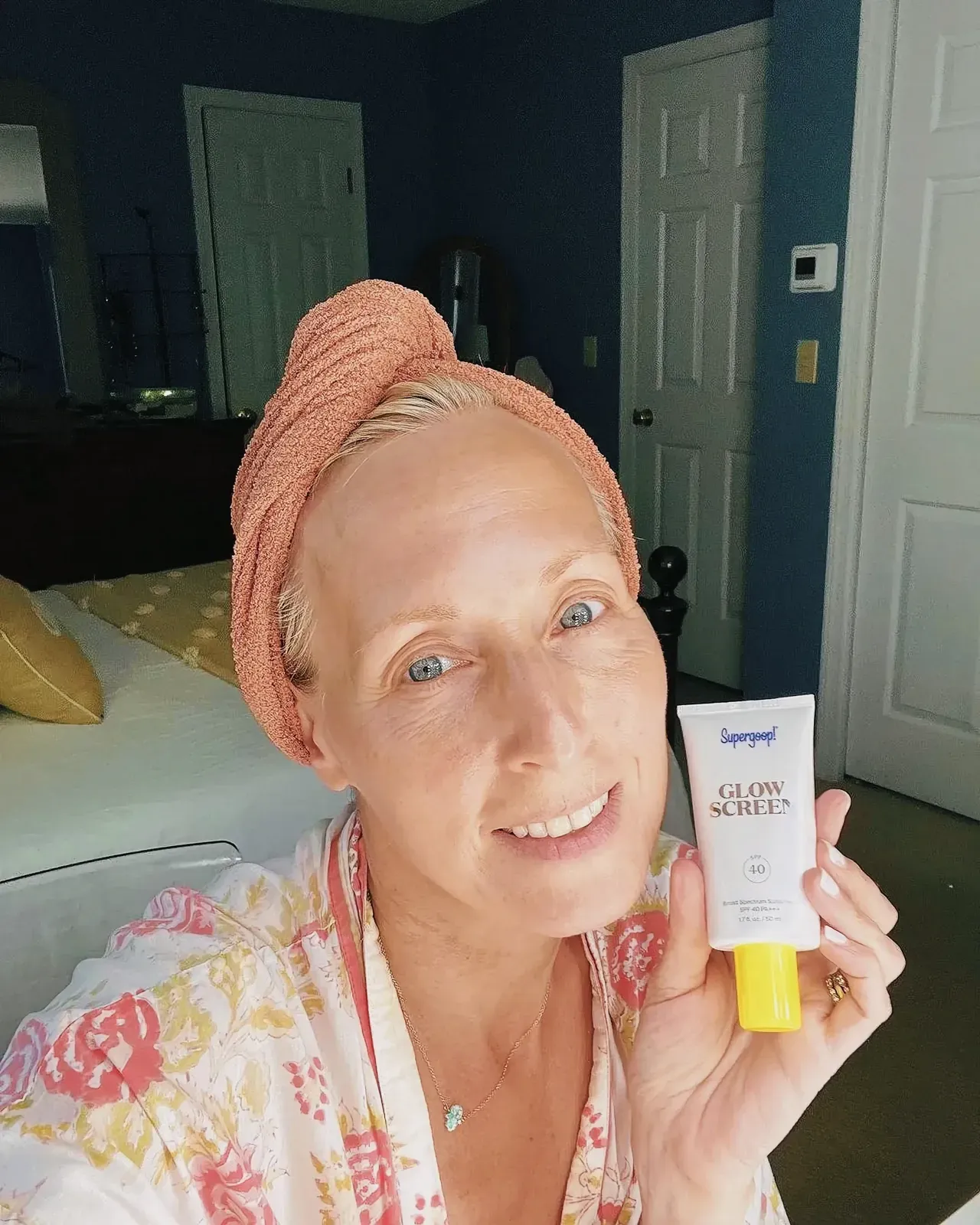 Cheerful woman presenting a tube of cream with her elegant hands