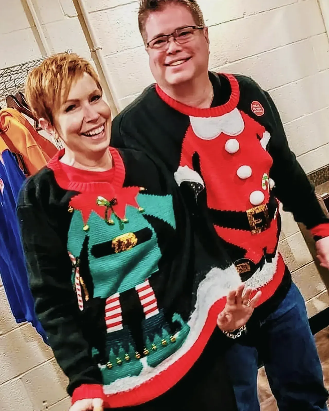 Joyful man and woman wearing vibrant Christmas sweaters.