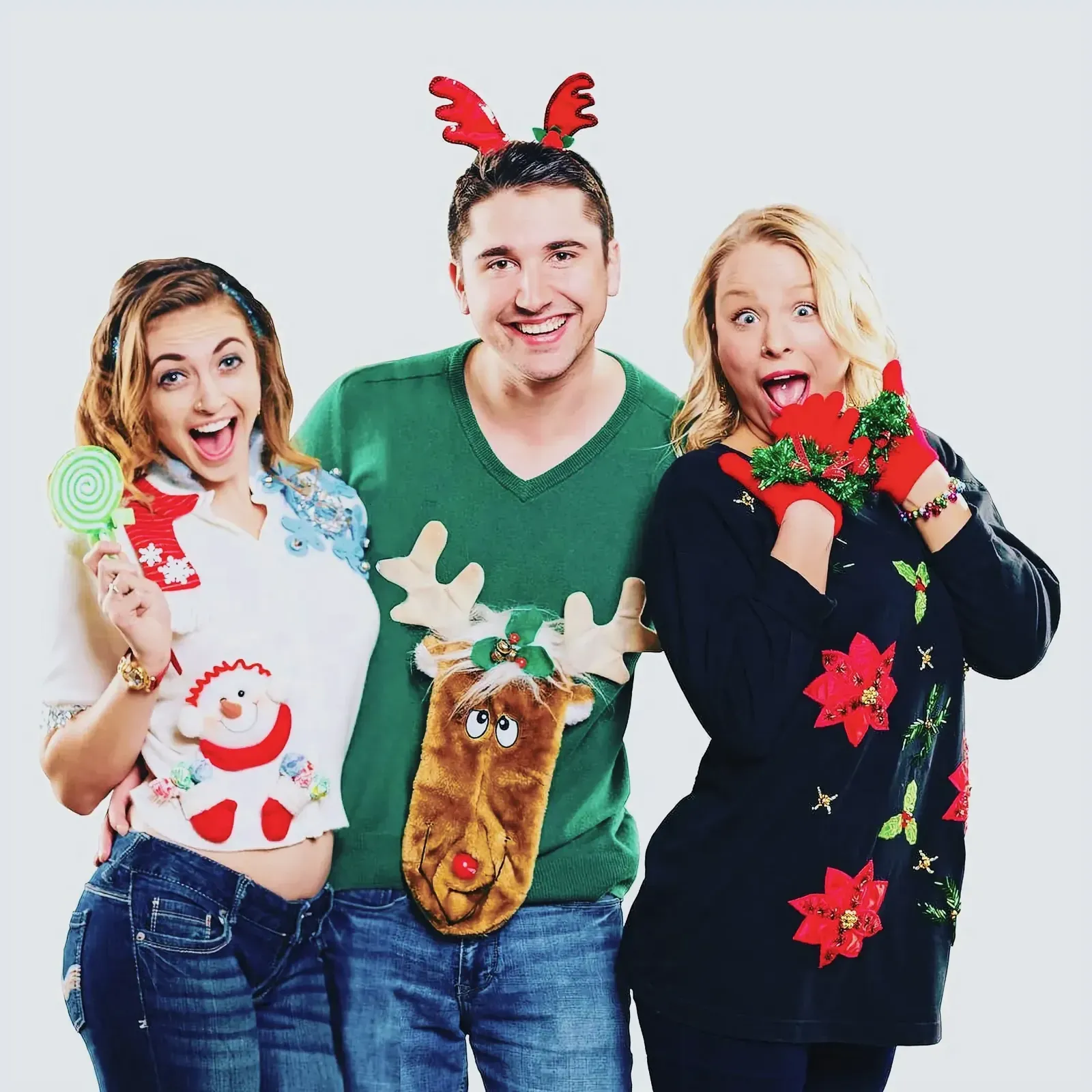 Group of three individuals in festive sweaters and accessories, posing for a picture