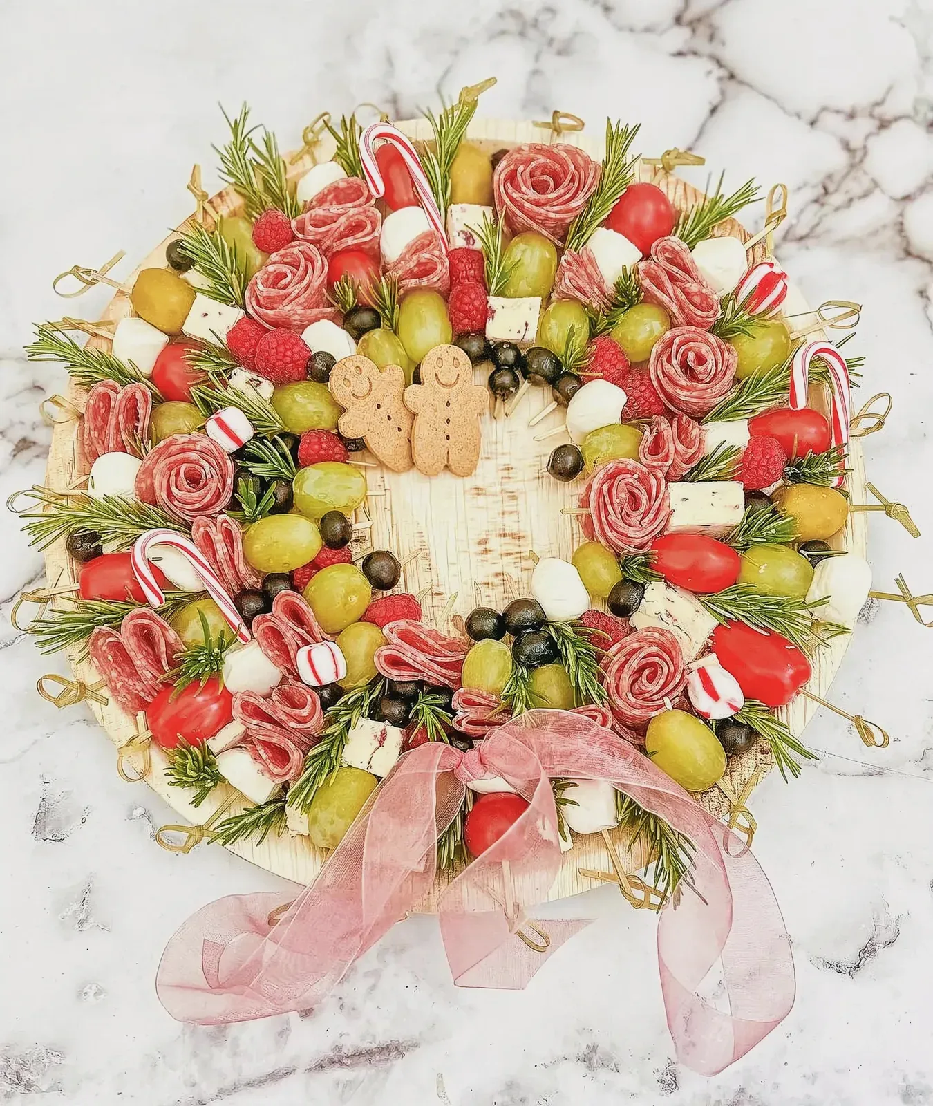 Beautifully arranged holiday platter with gingerbread men, grapes, marshmallows, melon, and strawberries