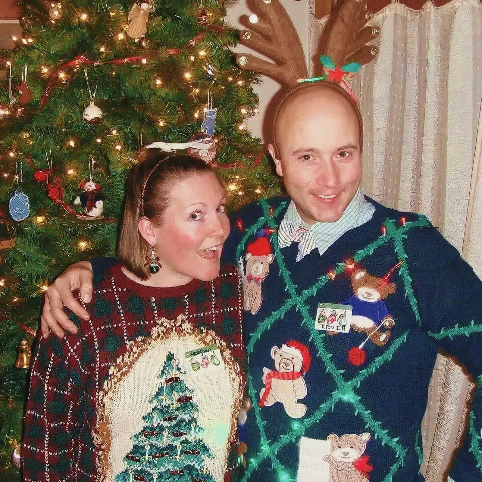 Jovial man and woman in front of a festively decorated Christmas tree