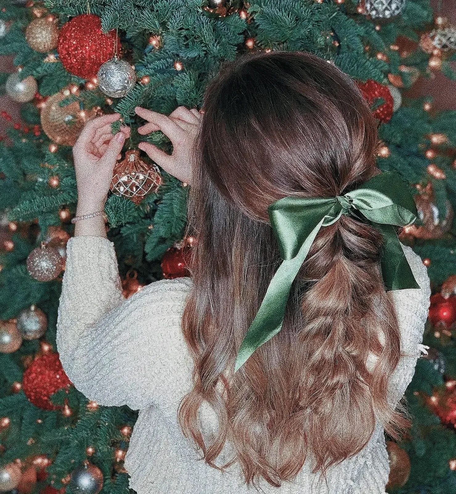 Festive woman with green bow in her hair holding a silver Christmas ornament