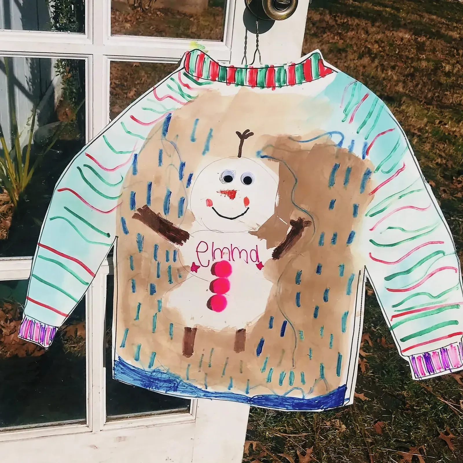 Whimsically illustrated, festive sweater hanging on a door handle.