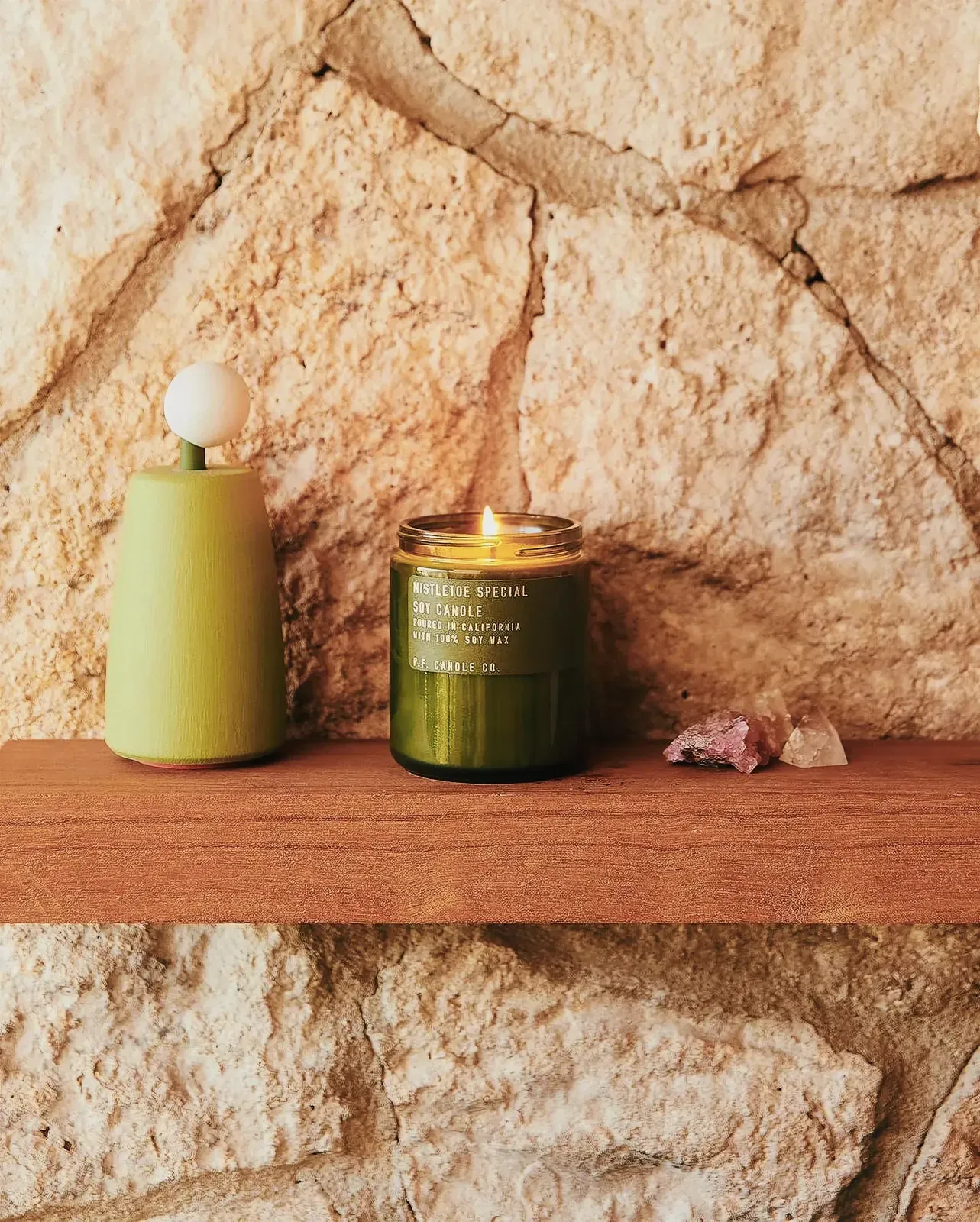 Candles on a wooden shelf with rustic stone wall background