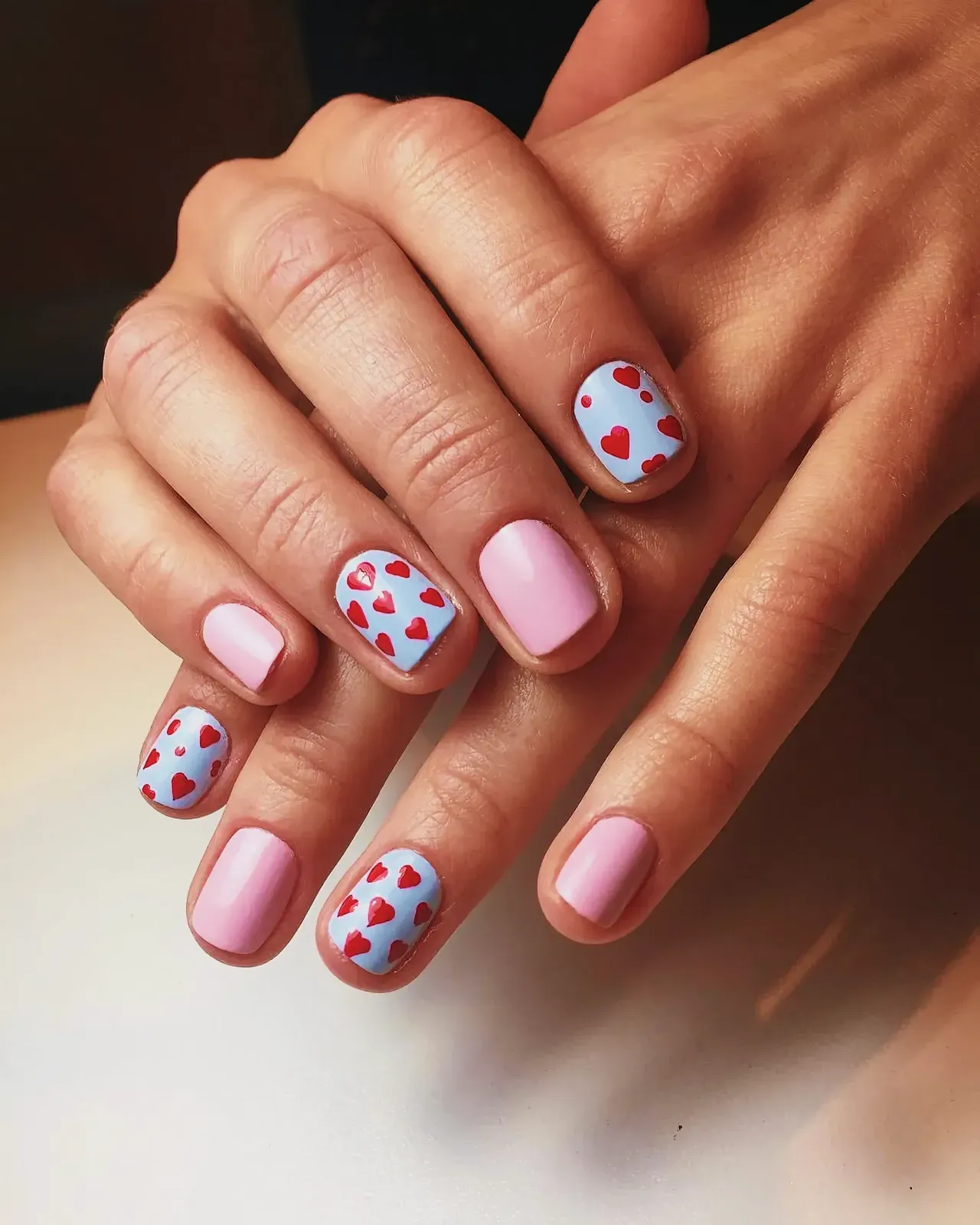 Close-up of meticulously painted fingernails with red heart designs