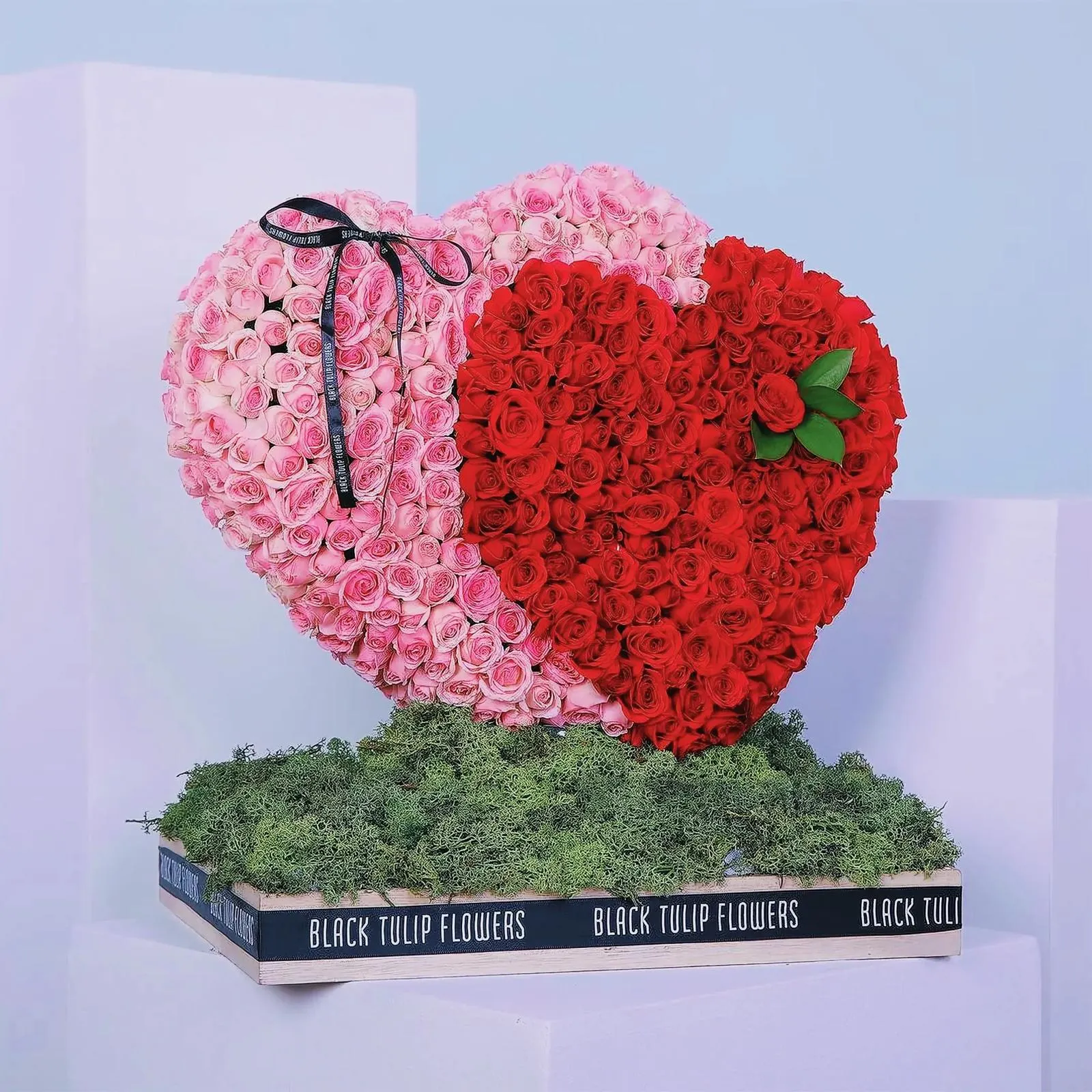 Intricate heart-shaped flower arrangement with roses and green plants