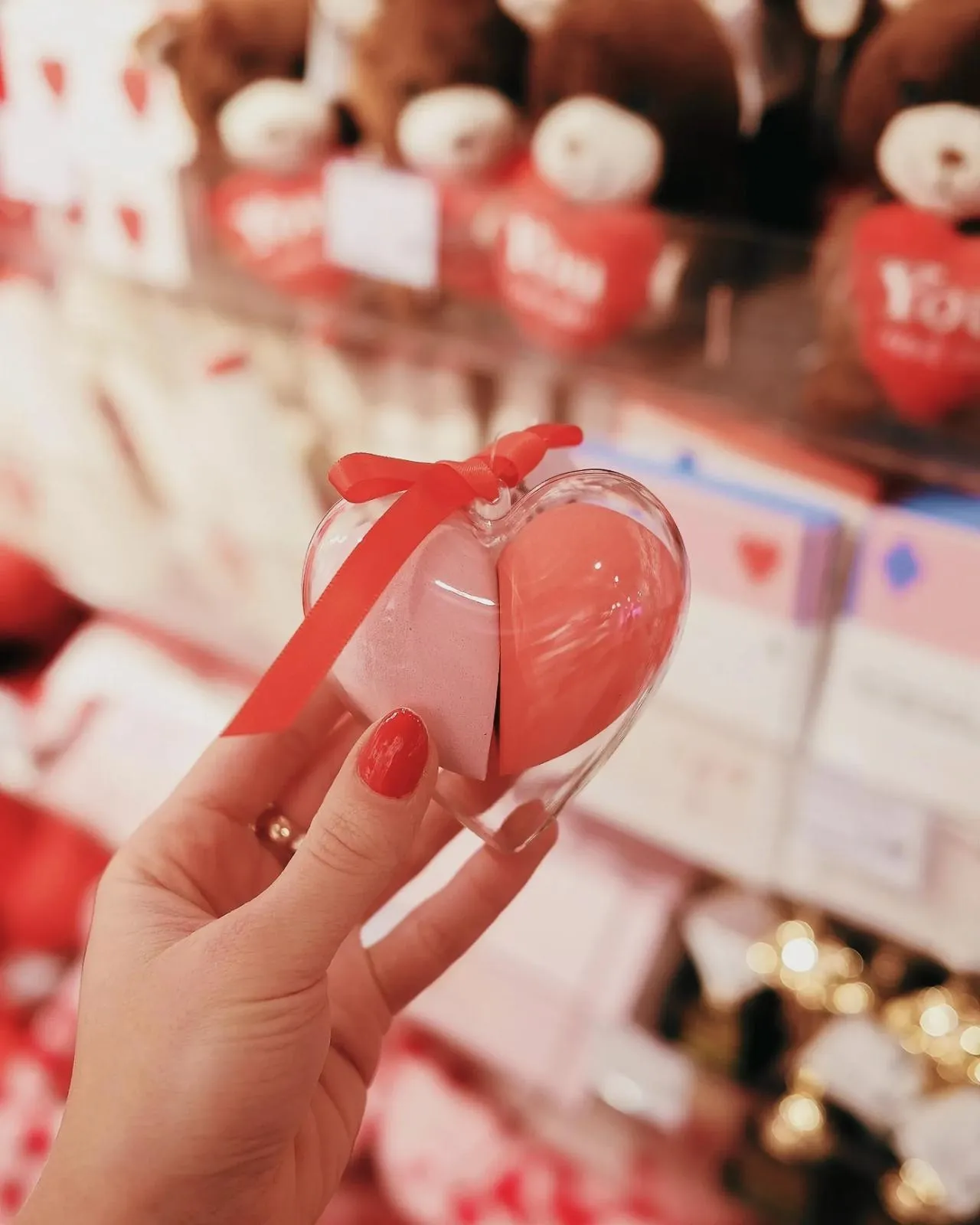 Person holding a heart-shaped box with a red ribbon